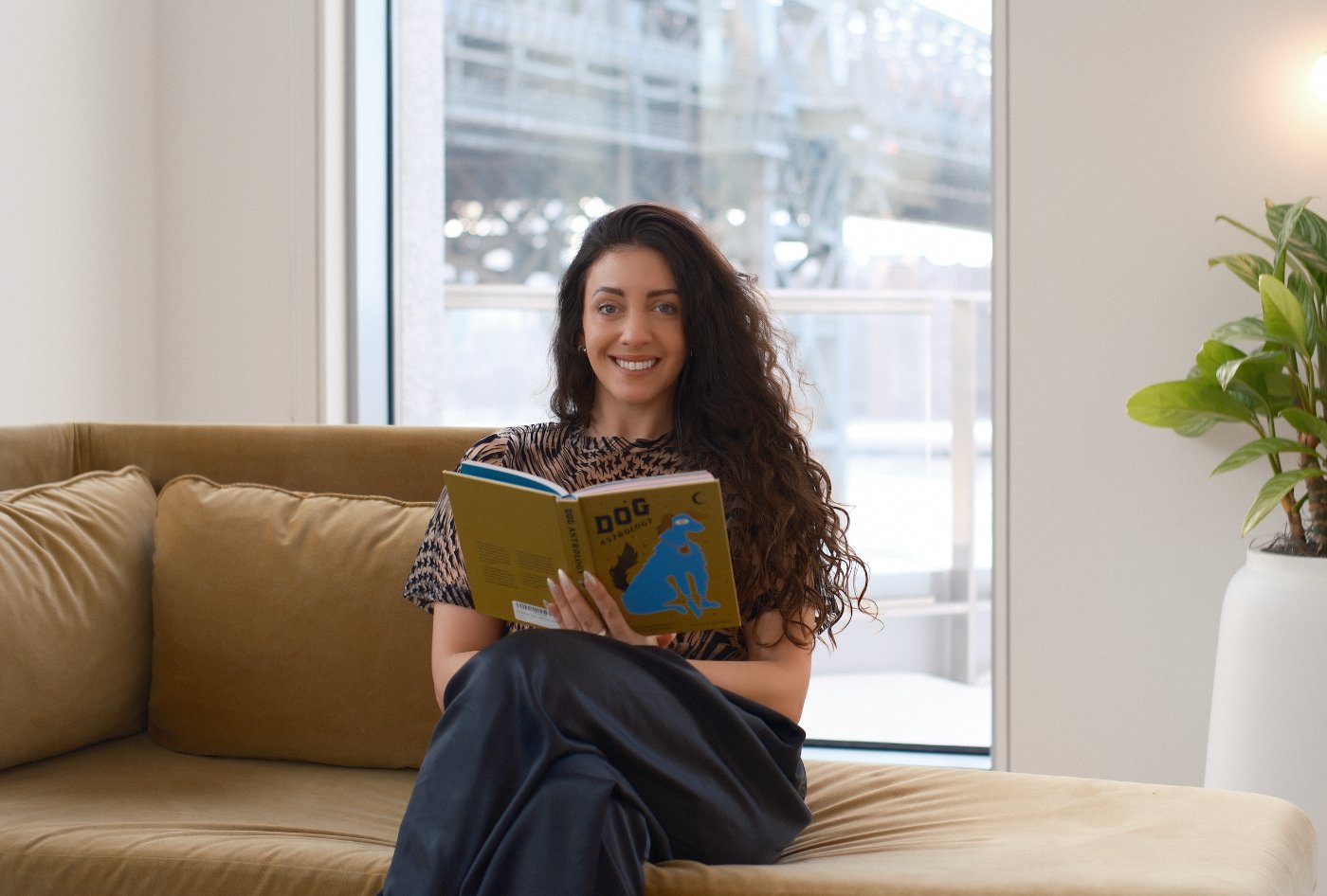 Bruna Fabregat at home on her sofa, reading a book about dog astrology